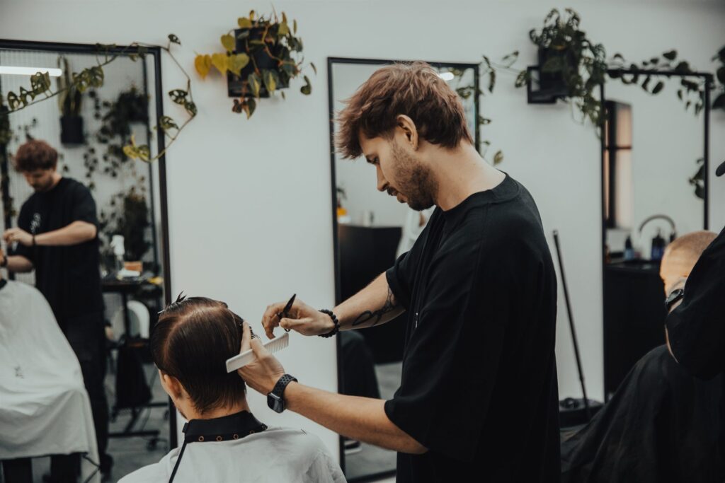 Wnętrze barbershopu Pracownia Męskich Fryzur – dwóch barberów w Bielsku-Białej podczas strzyżenia klientów